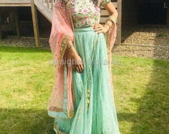 Op de afbeelding: Een mintgroene en roze Indiase outfit met gouden borduurwerk. De outfit bestaat uit een lange rok, een top met korte mouwen en een doorschijnende dupatta.