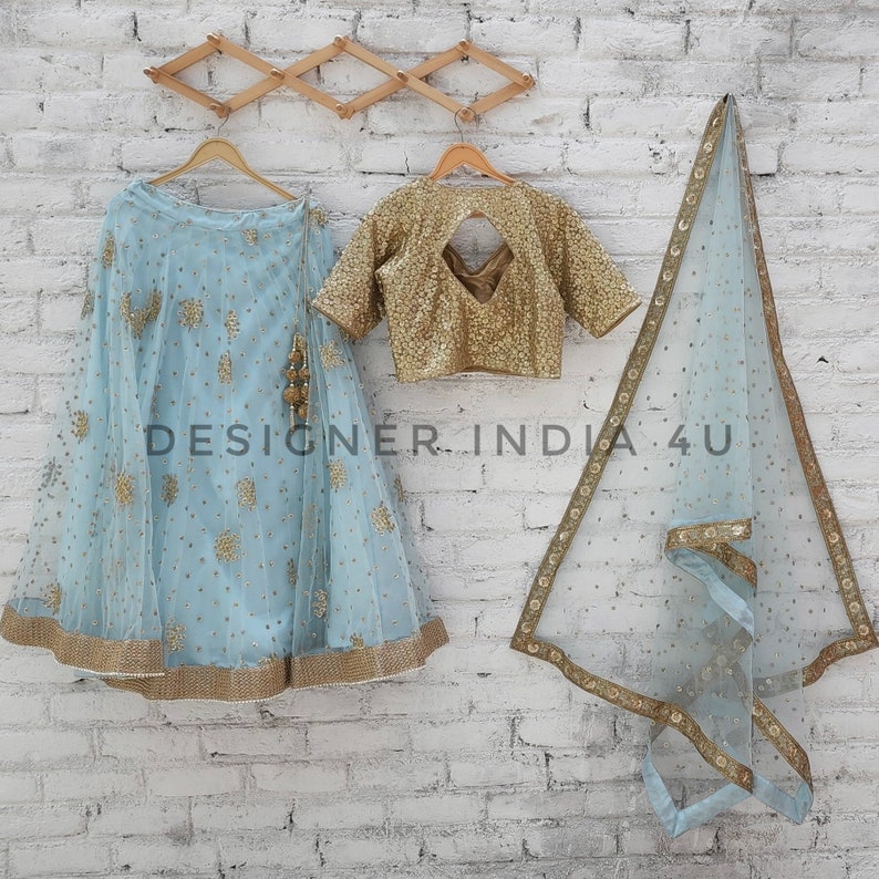 May include: A light blue embroidered skirt with gold trim, a gold embroidered blouse with a keyhole back, and a matching light blue sheer dupatta with gold trim. The text "DESIGNER INDIA 4U" is visible in the image.