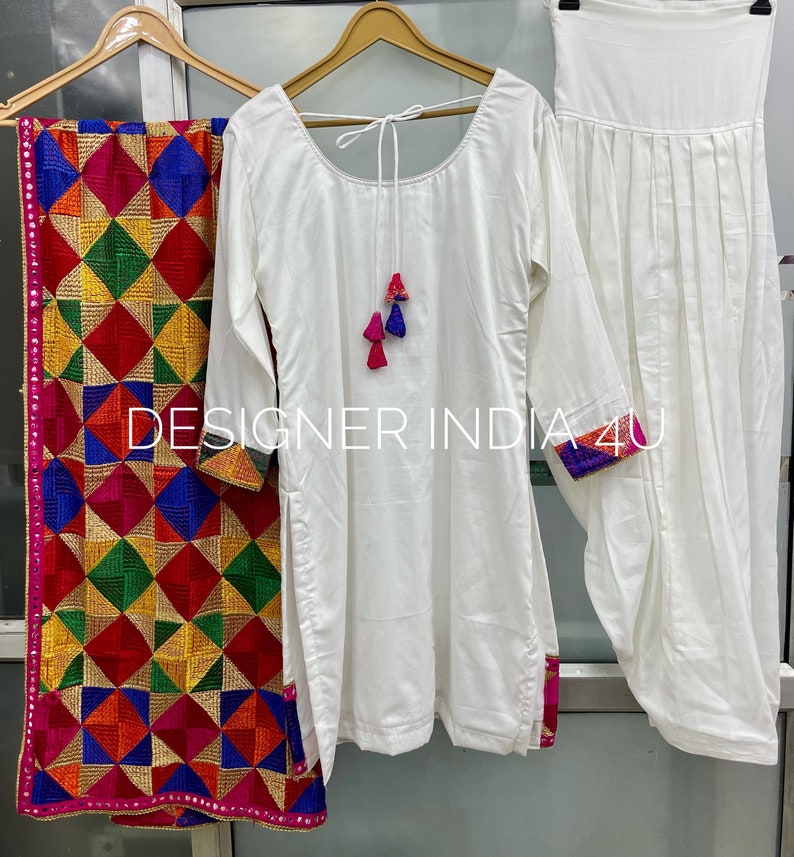Pu&ograve; includere: Completo salwar kameez bianco con un dupatta ricamato a colori. Il kameez ha una scollatura rotonda e maniche lunghe. Il salwar &egrave; bianco semplice e il dupatta ha un motivo geometrico.