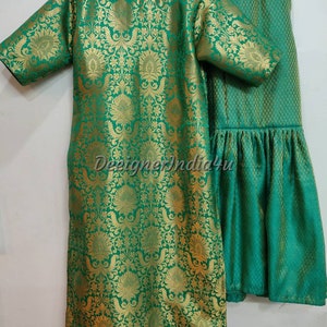 May include: A green and gold brocade ensemble featuring a tunic and matching pants. The tunic has short sleeves and a round neckline. The fabric is patterned with a floral design. The pants have a flared hem. The text "DesignerIndia4u" is visible.