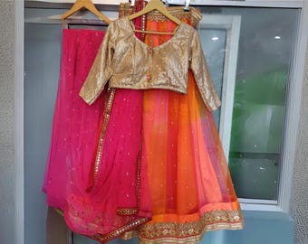 May include: A pink and orange layered skirt with gold embroidery and a matching gold sequined blouse with long sleeves.