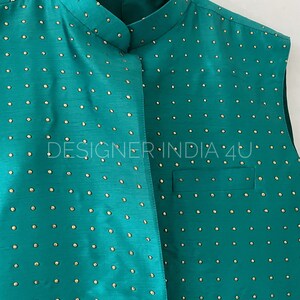 May include: A teal sleeveless vest with a mandarin collar and gold-colored polka dots. The vest is made of a smooth, silky fabric.