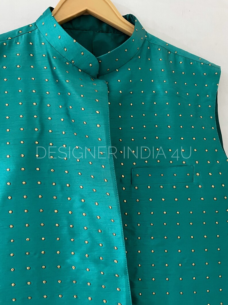 May include: A teal sleeveless vest with a mandarin collar and gold-colored polka dots. The vest is made of a smooth, silky fabric.