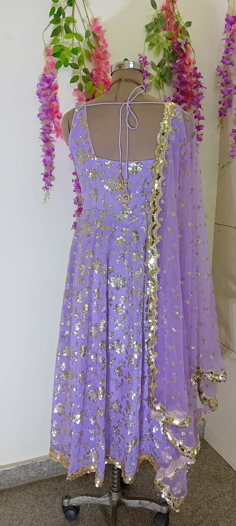 May include: A lavender-colored dress with gold sequins and a matching sheer dupatta. The dress has a scoop neckline and a tie-up back.