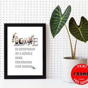 May include: A black framed print with a white background and a floral design spelling out the word "LOVE". The text below the floral design reads "LOVE IS COMPOSED OF A SINGLE SOUL INHABITING TWO BODIES".