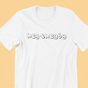 May include: White t-shirt with the text "hey theyby" in a bubble font.