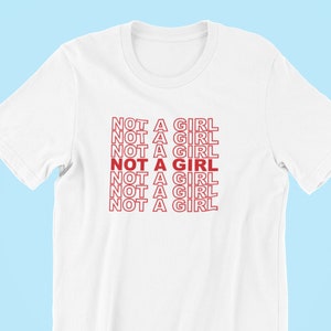 May include: White t-shirt with the phrase "NOT A GIRL" repeated in red text.