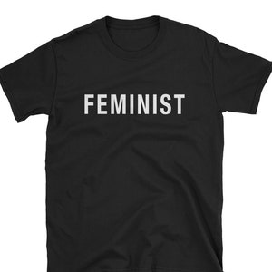 May include: Black short-sleeved t-shirt with the word "FEMINIST" printed in white on the front.