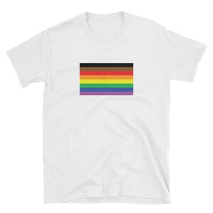 May include: White t-shirt with a multi-colored pride flag printed on the front. The flag has black, brown, orange, yellow, green, blue, and purple stripes.