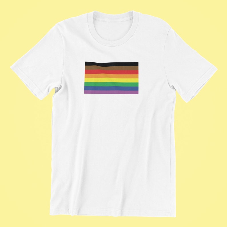 May include: White t-shirt with a rainbow pride flag printed on the front. The flag has black, brown, red, orange, yellow, green, blue, and purple stripes.