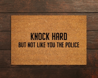 May include: A brown doormat with the text "Knock hard but not like you the police" printed in black.