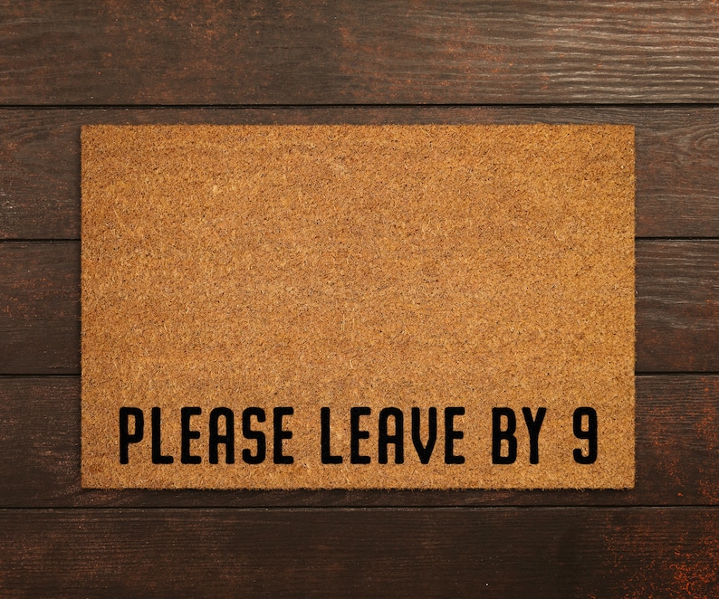 May include: A brown coir doormat with the text "PLEASE LEAVE BY 9" in black lettering.