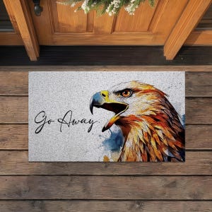 May include: A rectangular doormat with a watercolor illustration of an eagle's head, featuring shades of brown, orange, and blue. The text "Go Away" is written in a cursive font on the left side of the mat.