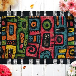 May include: Rectangular doormat with a colorful abstract design. The mat features vertical panels in various colors, including green, orange, red, and blue, with geometric shapes and patterns. The border is black and white checkered.