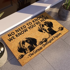 May include: A brown doormat with the text "No need to knock we know you're here - The German Shorthaired Pointers" and two black and white German Shorthaired Pointers peeking over the top.