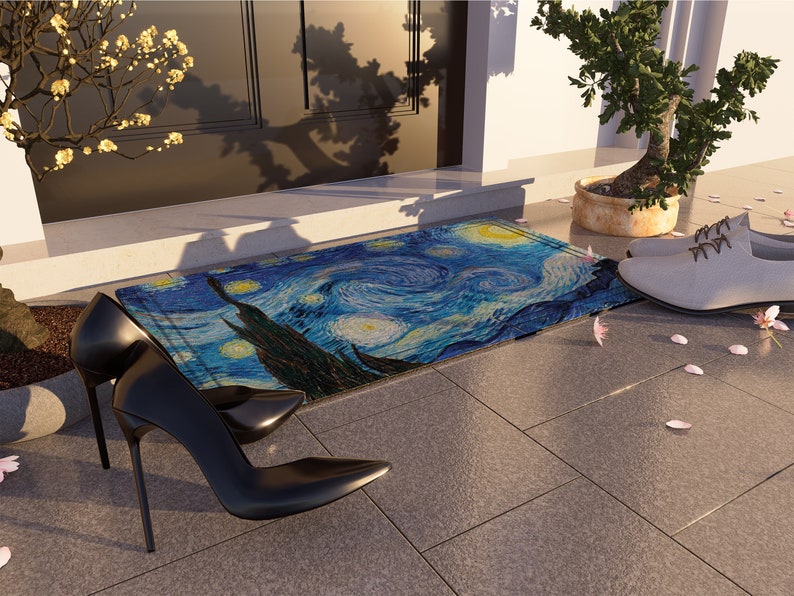 May include: A blue and yellow doormat with a painting of a starry night. The doormat is on a gray tiled floor with pink flower petals scattered around it. Two black high-heeled shoes are on the floor next to the doormat.