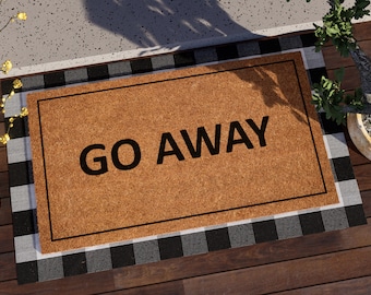 Puede incluir: Una alfombra de coco marrón con ribete negro y un borde a cuadros blanco y negro. La alfombra tiene el texto "GO AWAY" impreso en negro.