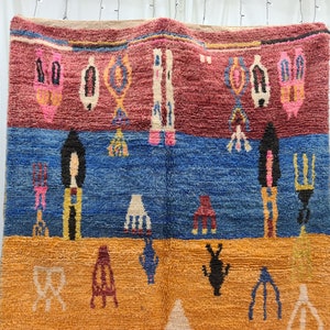 May include: A colorful Moroccan rug with geometric patterns in shades of red, blue, yellow, and white. The rug is woven with a thick, textured pile.