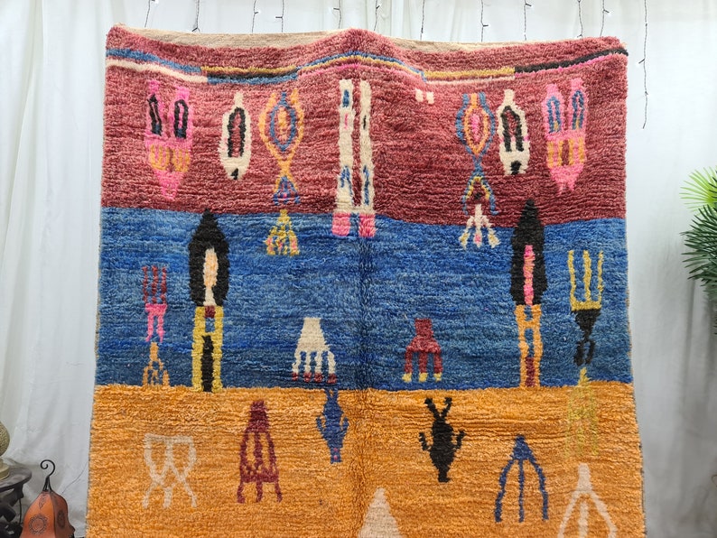 May include: A colorful Moroccan rug with geometric patterns in shades of red, blue, yellow, and white. The rug is woven with a thick, textured pile.
