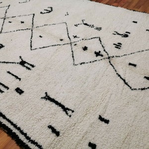 May include: White rug with a black geometric pattern. The pattern features diamonds and other abstract shapes.