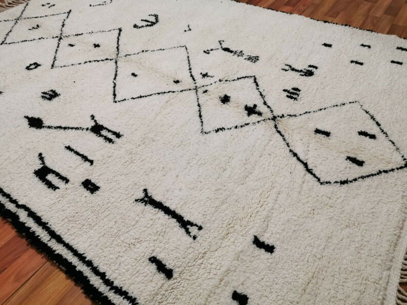 May include: White rug with a black geometric pattern. The pattern features diamonds and other abstract shapes.