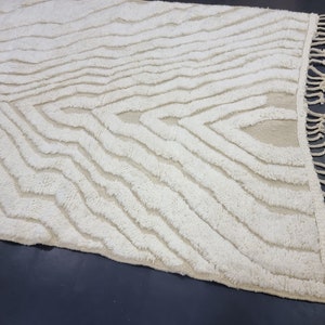 May include: A white, fluffy rug with a wavy, abstract pattern. The rug has a fringe border.
