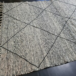 May include: Black and white rug with a diamond pattern and fringe on the edges.