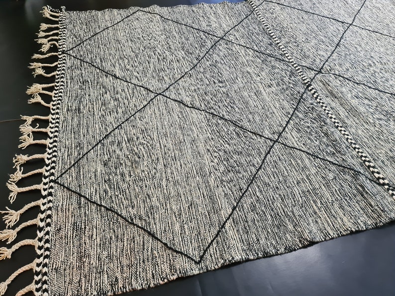 May include: Black and white rug with a diamond pattern and fringe on the edges.