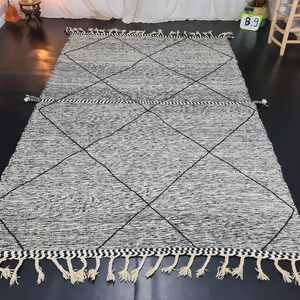 May include: A black and white diamond patterned rug with fringe. The rug has a subtle distressed look.