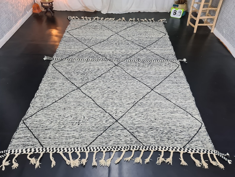 May include: A black and white diamond patterned rug with fringe. The rug has a subtle distressed look.