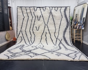 May include: A white and black Moroccan rug with a geometric pattern. The rug has a thick, fluffy pile and is made of wool.