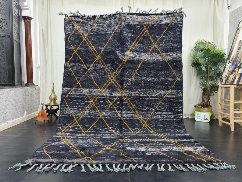 May include: A black and white Moroccan rug with a geometric pattern of yellow diamonds. The rug has a fringe border.