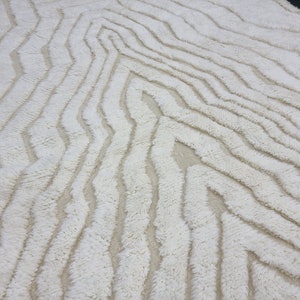 May include: White shag rug with a wavy, abstract pattern. The rug has a soft, fluffy texture.