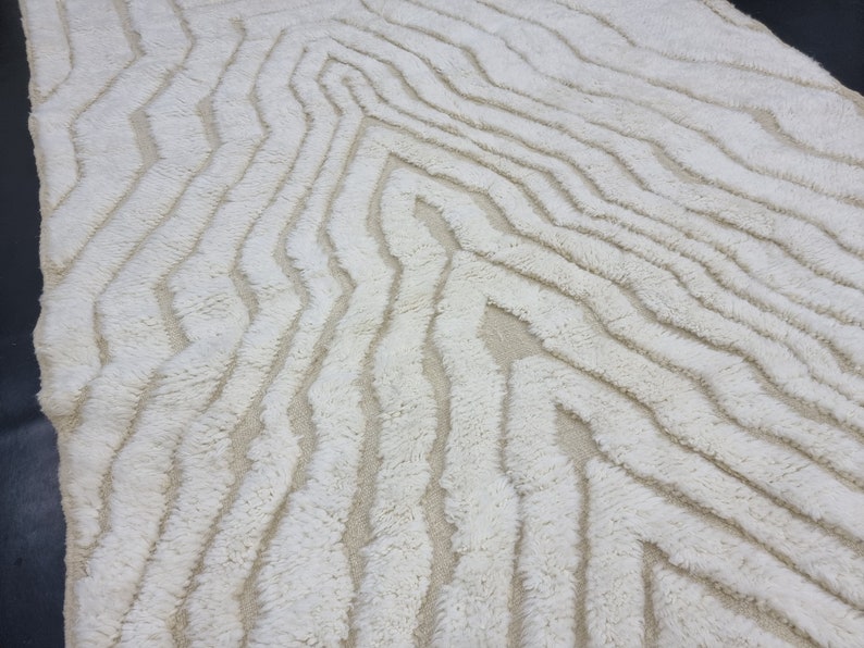 May include: White shag rug with a wavy, abstract pattern. The rug has a soft, fluffy texture.