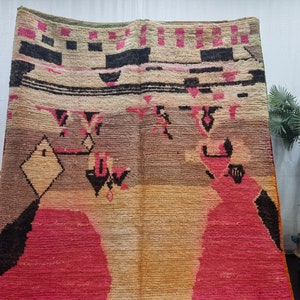 May include: A colorful Moroccan rug with geometric patterns in shades of pink, black, beige, and brown. The rug has a distressed, vintage look.