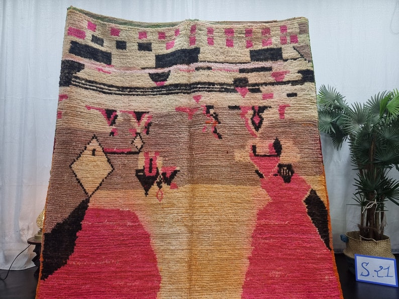 May include: A colorful Moroccan rug with geometric patterns in shades of pink, black, beige, and brown. The rug has a distressed, vintage look.