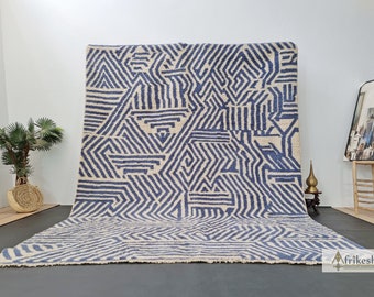 Può includere: Un tappeto geometrico blu e bianco con un design moderno. Il tappeto è in lana e ha una texture morbida e soffice.