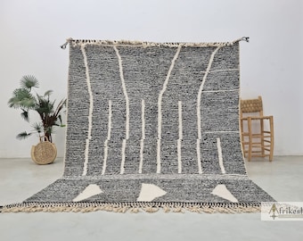 May include: A black and white Moroccan rug with a geometric pattern. The rug has a fringe border and is made of wool.