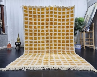 May include: A white and yellow Moroccan rug with a geometric pattern. The rug has a fringe border and is made of wool.