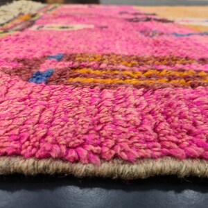 May include: Close-up of a pink and brown woven rug with a fringe border. The rug has a textured, fuzzy surface.