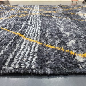 May include: A close-up of a gray and white rug with yellow stripes. The rug has a soft, fuzzy texture.