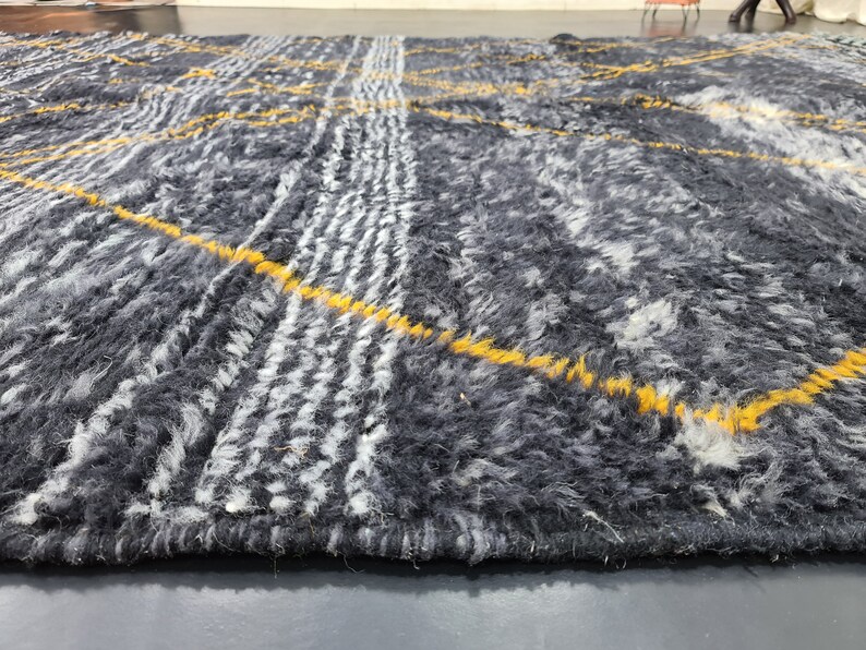 May include: A close-up of a gray and white rug with yellow stripes. The rug has a soft, fuzzy texture.