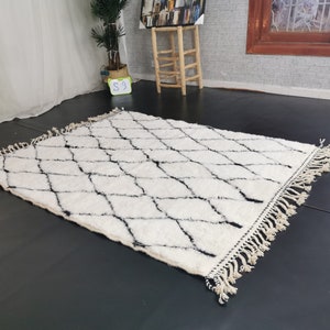 May include: A white and black diamond patterned rug with fringe. The rug is made of a soft, fluffy material.