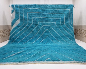 May include: A teal blue rug with a white geometric pattern. The rug has a fringe border.