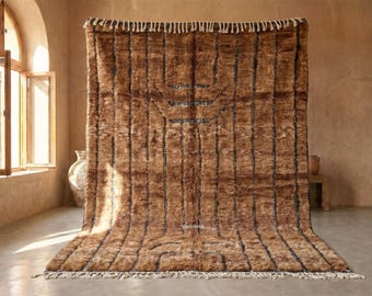 May include: A large, brown rug with vertical black stripes and a geometric design. The rug has a shaggy texture and a fringe along the bottom edge. The rug is displayed in a room with a window and a neutral color palette.