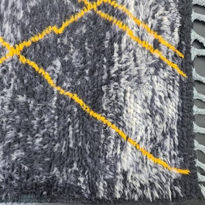 May include: A gray and white rug with yellow diamond patterns and fringe on the edges.