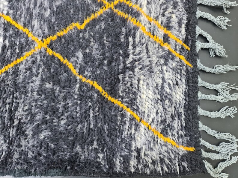 May include: A gray and white rug with yellow diamond patterns and fringe on the edges.