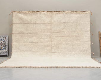 May include: A white woven rug with a fringe border. The rug has a subtle texture and a simple design.
