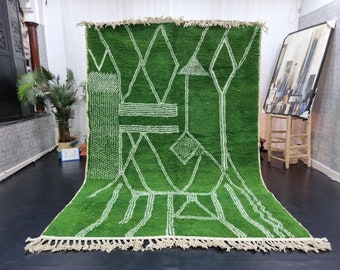Könnte beinhalten: Ein grüner marokkanischer Teppich mit einem weißen geometrischen Muster. Der Teppich hat einen Fransenrand.
