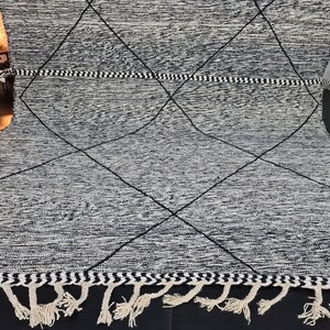 May include: Black and white diamond patterned rug with fringe. The rug has a woven texture and a simple design.